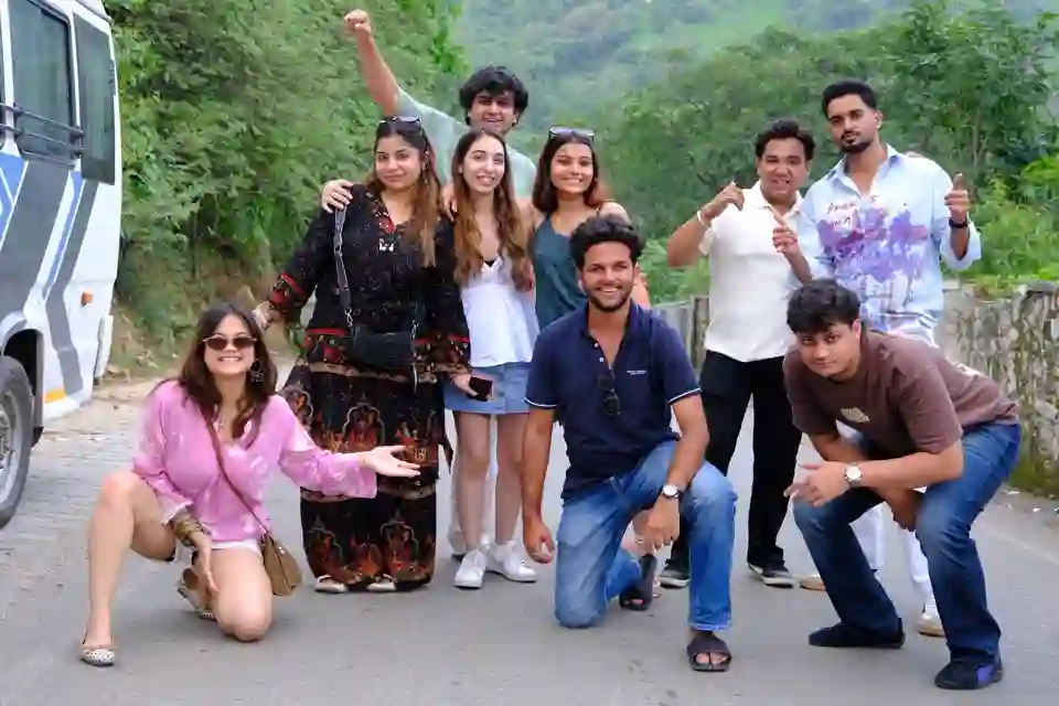 Travellers posing playfully beside the bus on a mountain road